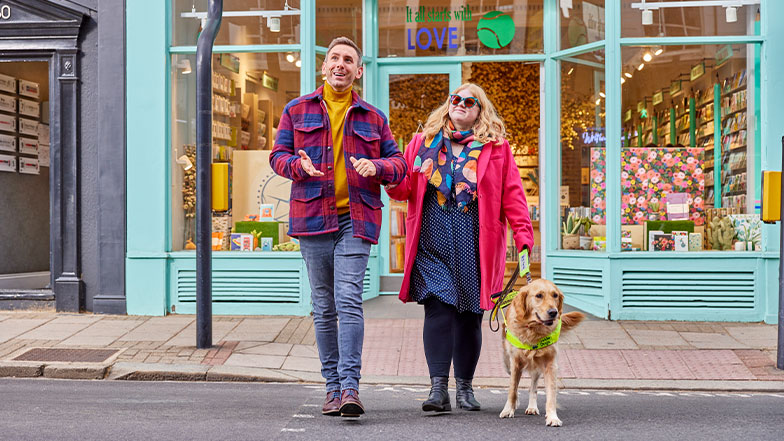 man guiding a guide dog owner across a road